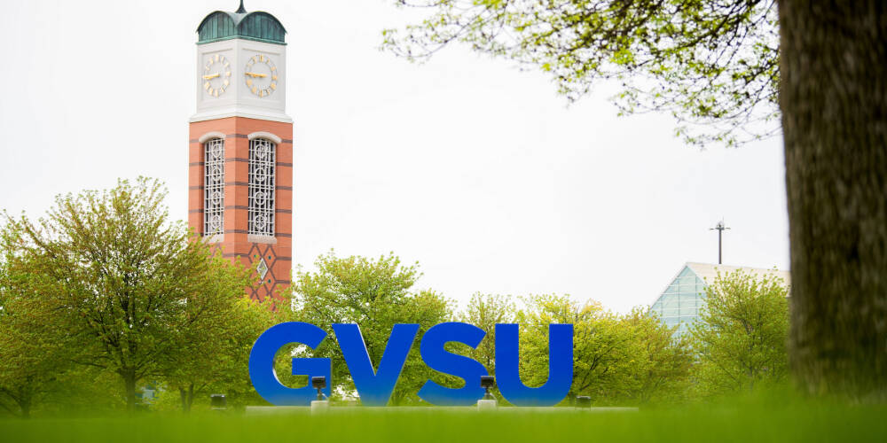 Exterior of GVSU's Valley Campus, with large GVSU letters in the foreground and clock tower in the background.